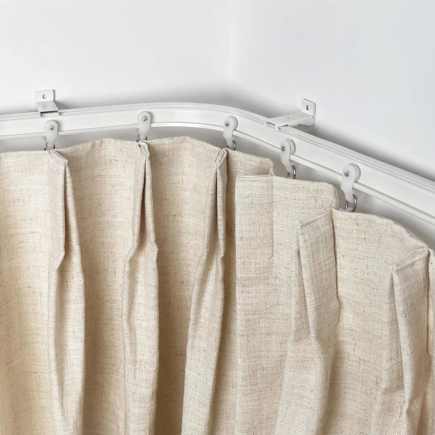 Close view of neutral curtains running smoothly around a tightly curved ceiling track