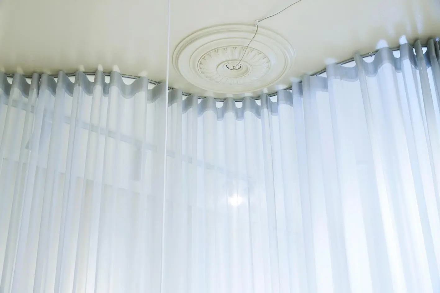 Blue wave curtains hung from a shaped ceiling track