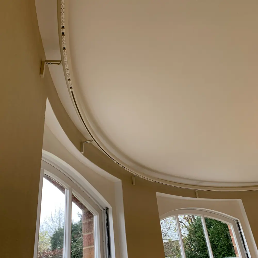 Precisely shaped ceiling curtain track around a bay window