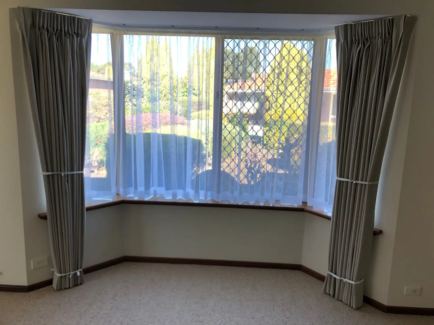 Pinch pleat curtains following an angled bay window